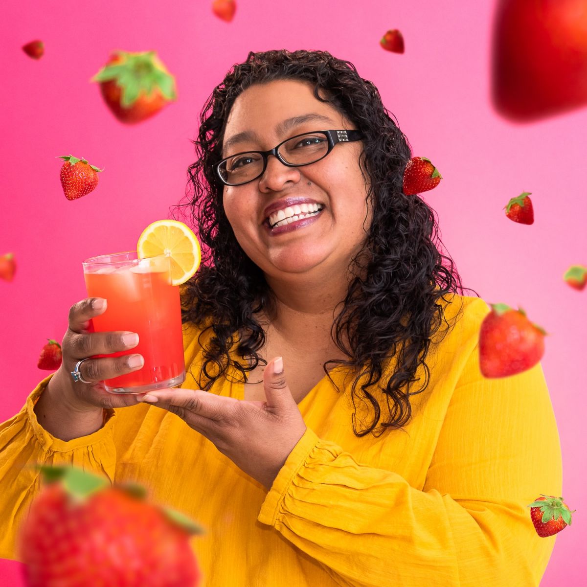 sandra cruz surrounded by strawberries and holding a drink