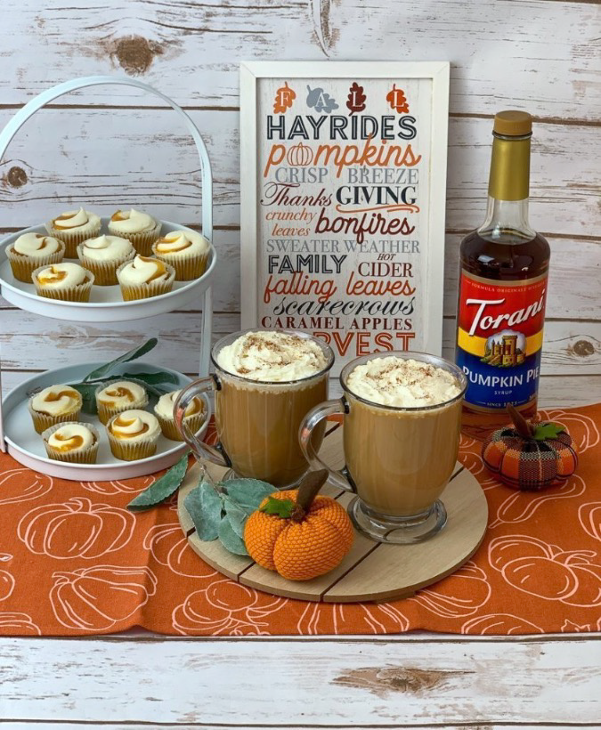 pumpkin spice lattes with pumpkin muffins and a bottle of torani pumpkin spice syrup