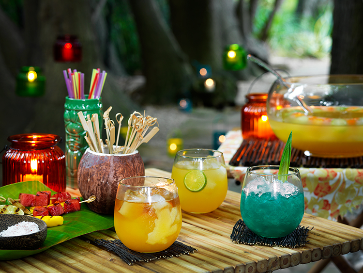 tropical scene with several mixed drinks and candles