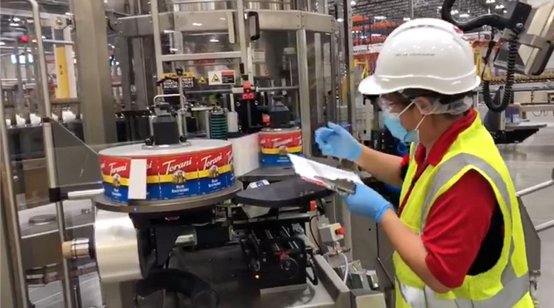 torani employee studying label machine in flavor factory